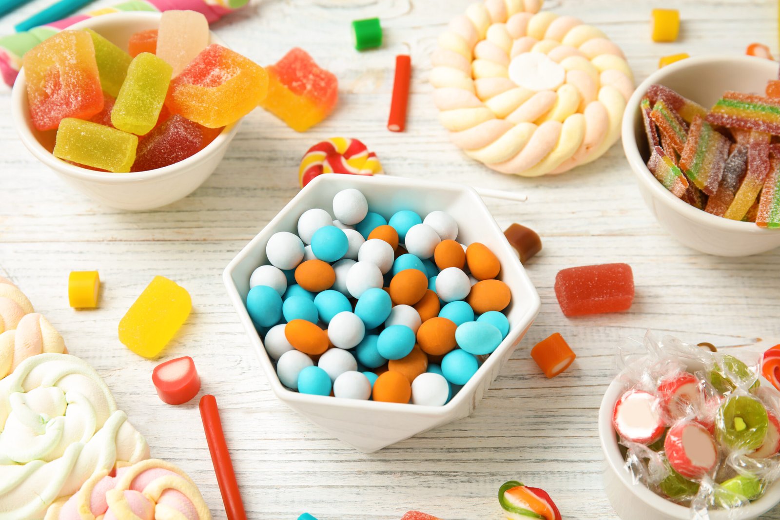 Composition with different yummy candies on white wooden table